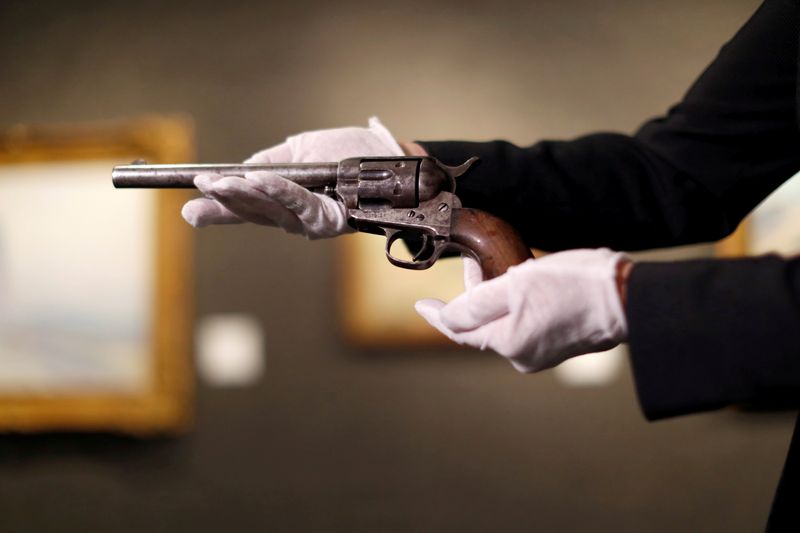 &copy; Reuters. FILE PHOTO: Catherine Williamson, Director of entertainment memorabilia at auction house Bonhams, holds the Colt single-action Army revolver used to kill Billy the Kid during a media preview in Los Angeles, California, U.S., August 5, 2021.  REUTERS/Mario