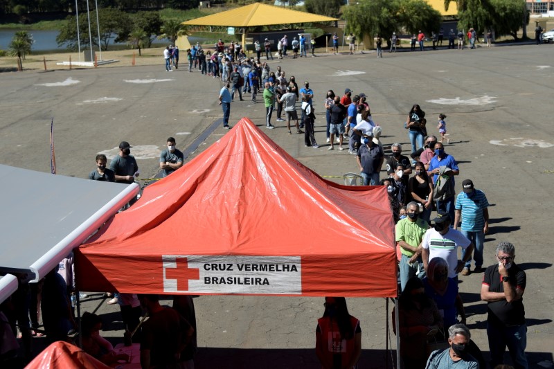 &copy; Reuters. FOTO DE ARCHIVO: Residentes hacen fila frente al "Busao da Vacina" o Gran autobús de la vacuna, un proyecto de la Cruz Roja Brasileña, en asociación con el gobierno del estado de Minas Gerais para vacunar a la gente contra la enfermedad del coronavirus