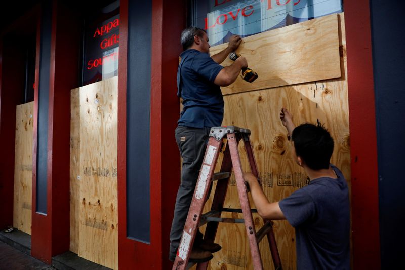 &copy; Reuters. Dos personas colocan paneles de madera en los escaparates de un tienda ante la llegada del huracán Ida, en Nueva Orleans, Luisiana, EEUU. 28 agosto 2021. REUTERS/Marco Bello