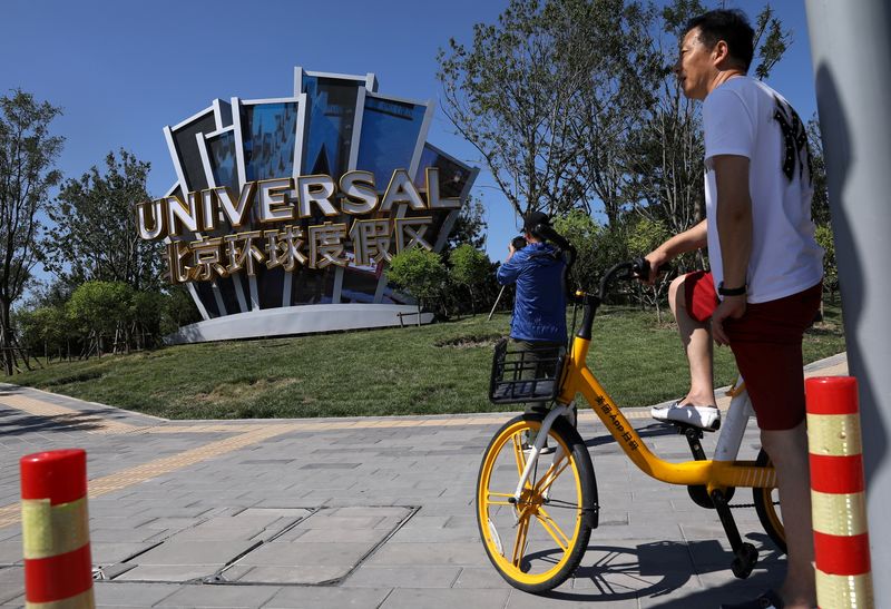 &copy; Reuters. FILE PHOTO: A man rides a bike of a bike-sharing service near a giant sign Universal Beijing Resort, ahead of its opening, in Beijing, China August 27, 2021. REUTERS/Tingshu Wang/File Photo