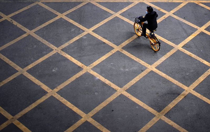 &copy; Reuters. Imagen de archivo de una persona usando mascarilla mientras usa una bicicleta de servicio compartido en una calle, casi un año después del inicio de la pandemia de COVID-19, en Wuhan