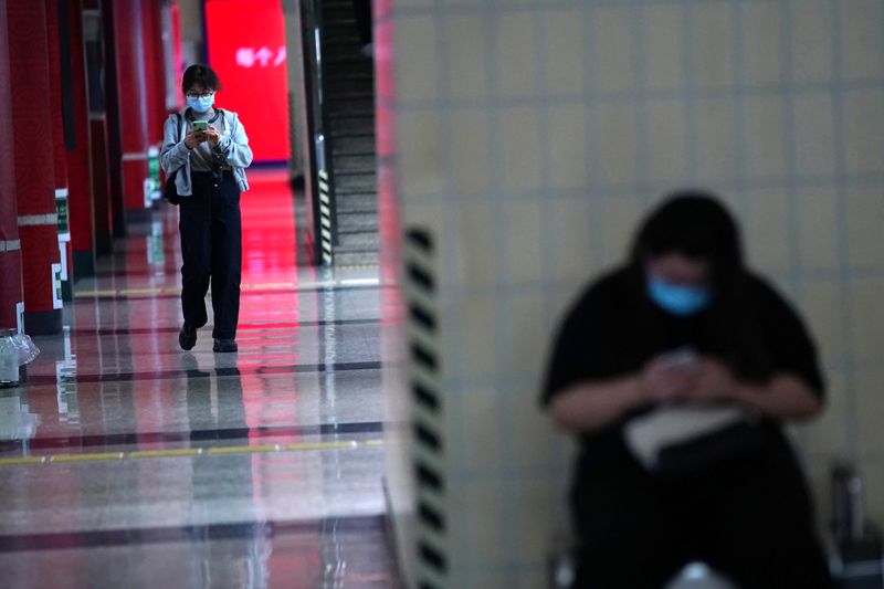 &copy; Reuters. Pasajeros con mascarillas utilizan sus teléfonos en una estación de metro de Pekín, China