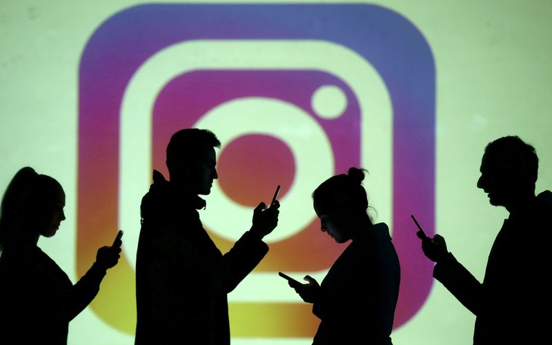 &copy; Reuters. FILE PHOTO: Silhouettes of mobile users are seen next to a screen projection of Instagram logo in this picture illustration taken March 28, 2018.  REUTERS/Dado Ruvic/Illustration