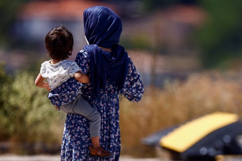 © Reuters. An Afghan evacuee carrying a child walks at a holding centre run by the Italian Red Cross, where she carries out a quarantine with others, in Avezzano, Italy, August 30, 2021. REUTERS/Guglielmo Mangiapane
