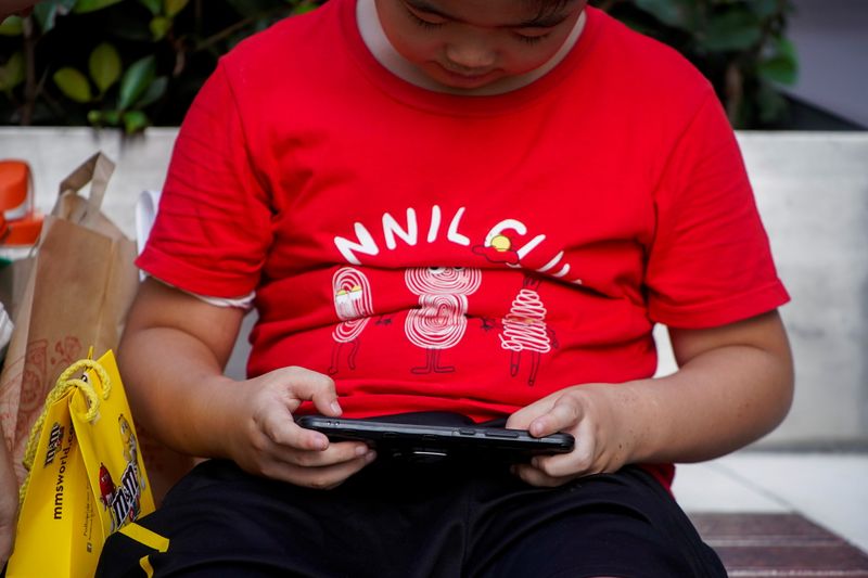 &copy; Reuters. A boy plays a game on a phone on a street in Shanghai, China August 31, 2021. REUTERS/Aly Song