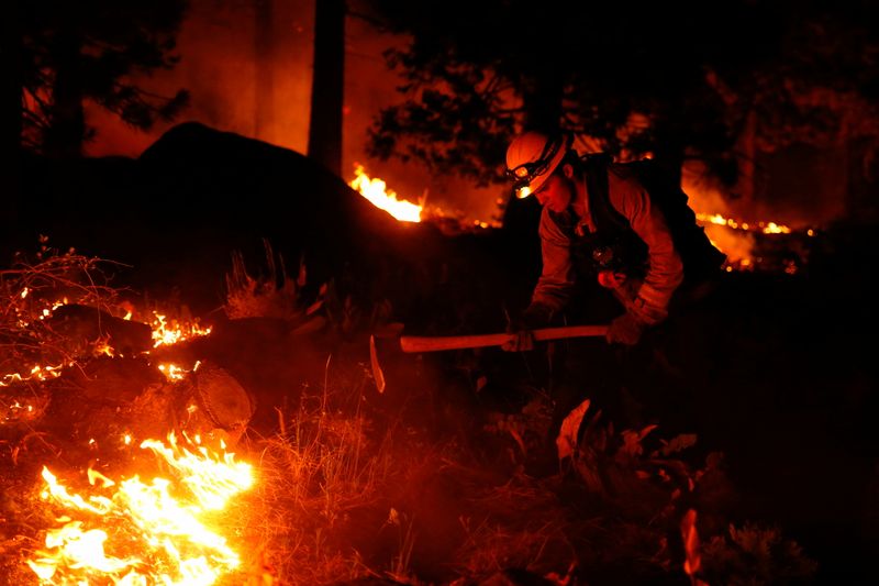 © Reuters. Austin Rhodes, 20, a fire fighter with the Fallen Leaf Lake Fire Department, works a hand line behind houses along Santa Clause Drive as flames from the Caldor Fire burn through trees in Christmas Valley near South Lake Tahoe, California, U.S., August 30, 2021.    REUTERS/Brittany Hosea-Small