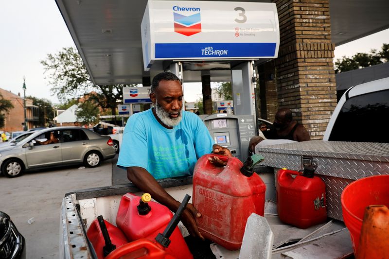 &copy; Reuters. FILE PHOTO: A man puts a container with gas in the back of his truck as people queue to fill cars and containers with gas at an open for business gas station after Hurricane Ida made landfall in Louisiana, in New Orleans, Louisiana, U.S. August 30, 2021. 