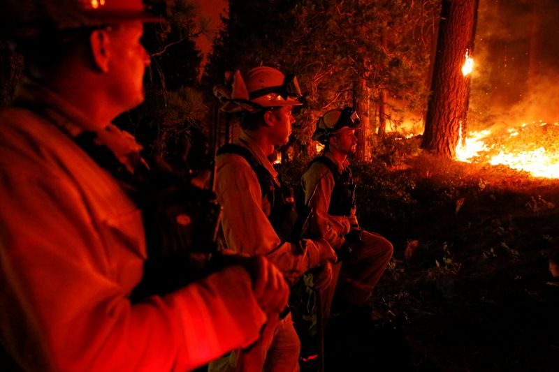 &copy; Reuters. FILE PHOTO: Darob Baker (right), 30, a fire engineer with the El Dorado County Fire Department, and his colleagues, Matt Ziebarth, 45, and fire captain Rob Sime, 44, work on structure protection along Santa Clause Drive as flames from the Caldor Fire burn