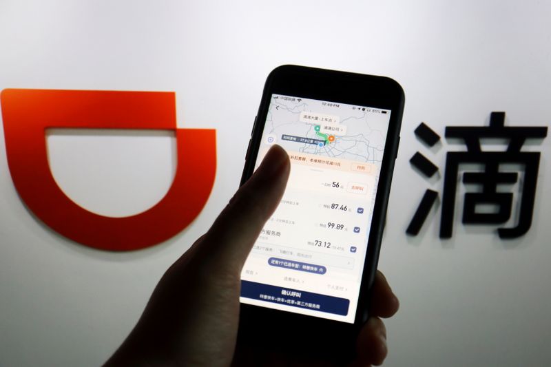 © Reuters. FILE PHOTO: The app of Chinese ride-hailing giant Didi is seen on a mobile phone in front of the company logo displayed in this illustration picture taken July 1, 2021. REUTERS/Florence Lo/Illustration/File Photo