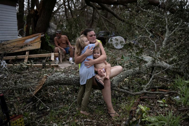 © Reuters. Tiffany Miller is embraced by her daughter Desilynn, 6, as she holds her one year old godchild Charleigh, after the family returned to their destroyed home in the aftermath of Hurricane Ida in Golden Meadow, Louisiana, U.S., September 1, 2021. REUTERS/Adrees Latif     