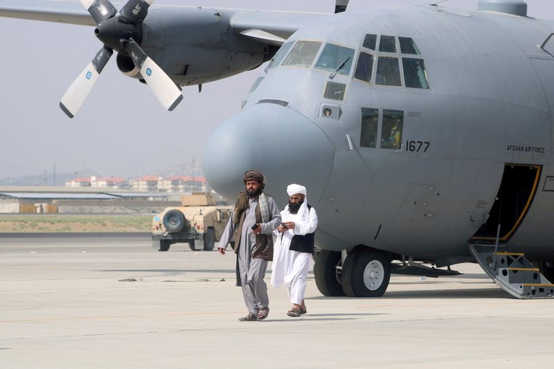 © Reuters. عضوان في حركة طالبان يسيران أمام طائرة عسكرية بعد انسحاب القوات الأمريكية من مطار حامد كرزاي الدولي في كابول يوم 31 أغسطس آب 2021. صورة لرويترز.
