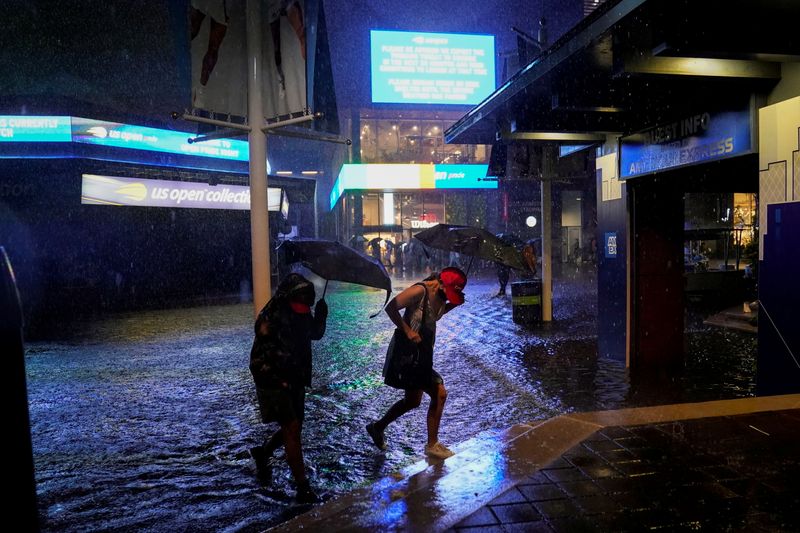 &copy; Reuters. Espectadores atravessam área inundada perto do estádio Louis Armstrong, no complexo onde é disputado o Aberto dos EUA de tênis, em Nova York
01/09/2021 Danielle Parhizkaran-USA TODAY Sports via REUTERS 