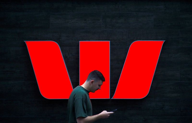 &copy; Reuters. FILE PHOTO: A pedestrian looks at his phone as he walks past a logo for Australia's Westpac Banking Corp located outside a branch in central Sydney, Australia, November 5, 2018.   REUTERS/David Gray