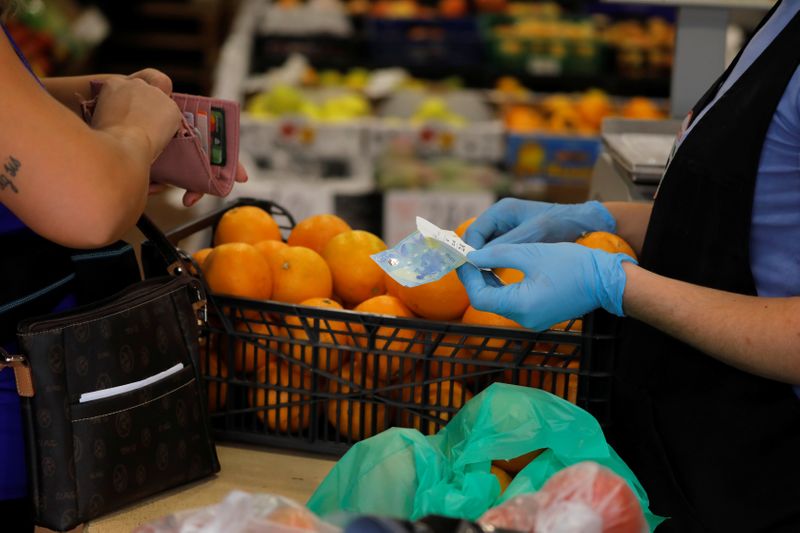 &copy; Reuters. Pessoa paga por suas compras em loja de frutas de Ronda, na Espanha, em meio a disseminação da Covid-19
09/10/2020
REUTERS/Jon Nazca