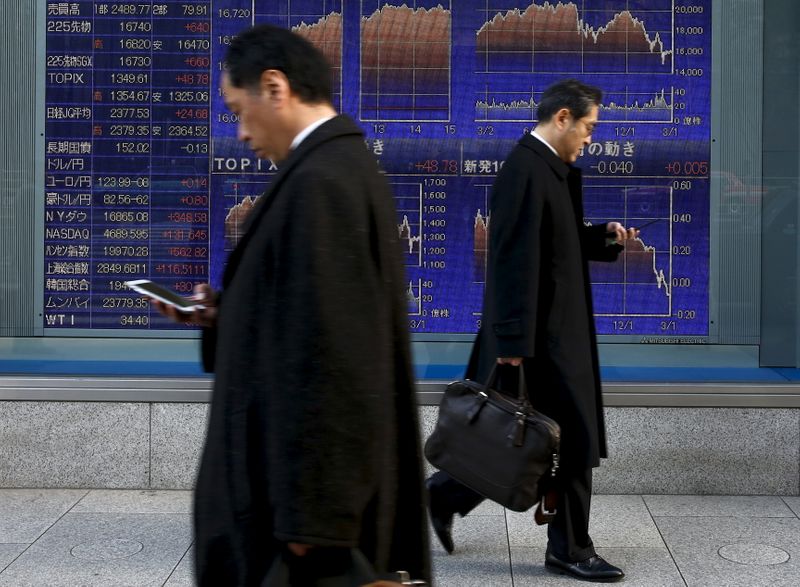 &copy; Reuters. Men walk past an electronic board showing market indices outside a brokerage in Tokyo, Japan,  March 2, 2016.  Japan's Nikkei surged to a more than three-week high on Wednesday as the dollar rose against the yen after strong U.S. factory and construction 