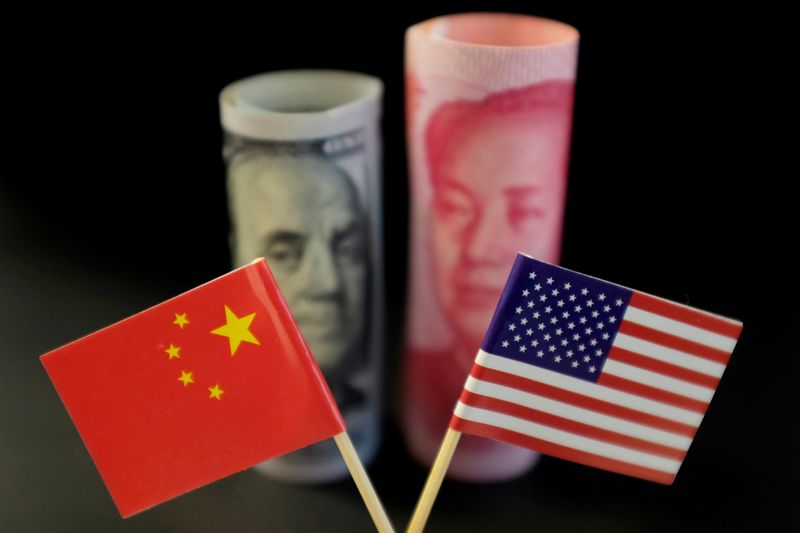 &copy; Reuters. Una bandiera cinese e una statunitense, davanti a una banconota da 100 dollari e una banconota da 100 yuan. REUTERS/Jason Lee