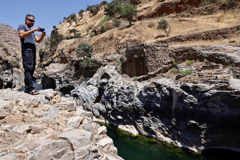 &copy; Reuters. نبيل موسى الناشط في حماية البيئة يلتقط صورا لنهر سروان في كردستان العراق يوم 13 يونيو حزيران 2021. تصوير: ثائر السوداني - رويترز.