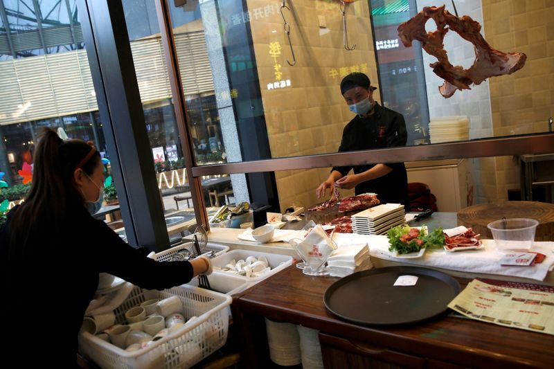 &copy; Reuters. FILE PHOTO: A chef wearing a face mask prepares beef as a waitress sorts tableware at a beef hotpot restaurant in Beijing, amid an outbreak of the novel coronavirus disease (COVID-19) in the country, China April 7, 2020. REUTERS/Tingshu Wang/File Photo