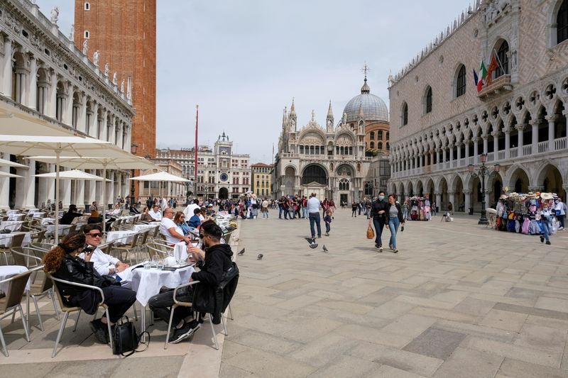 © Reuters. FILE PHOTO: People sit at outdoor tables in St. Mark's Square, Venice, Italy, May 16, 2021. REUTERS/Manuel Silvestri