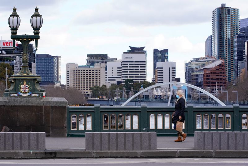 &copy; Reuters. FILE PHOTO: A lone woman, wearing a protective face mask, walks across an unusually quiet city centre bridge on the first day of a lockdown as the state of Victoria looks to curb the spread of a coronavirus disease (COVID-19) outbreak in Melbourne, Austra