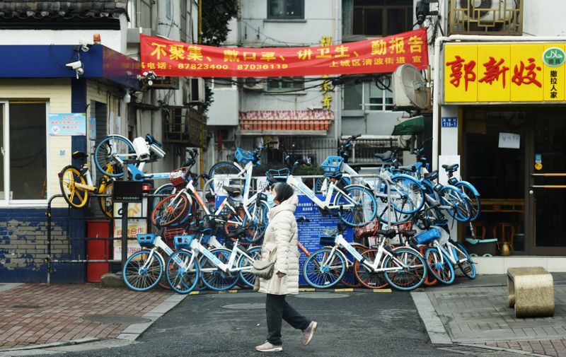 &copy; Reuters. FILE PHOTO-A woman wearing a face mask walks past an entrance to a residential compound that has been blocked by shared bicycles, as the country is hit by an outbreak of the novel coronavirus, in Hangzhou, Zhejiang province, China February 12, 2020. China