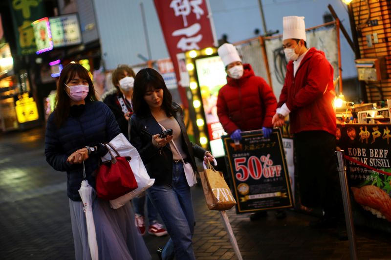 © Reuters. FOTO DE ARCHIVO: Personas, con mascarillas protectoras tras un brote de la enfermedad del coronavirus (COVID-19), caminan por una calle casi vacía en el distrito de ocio de Dotonbori, en Osaka, Japón, 14 de marzo de 2020.   REUTERS/Edgard Garrido