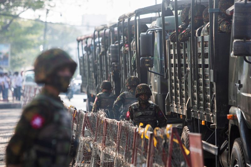 &copy; Reuters. جنود من جيش ميانمار يقفون بالقرب من مركبات عسكرية أثناء تجمع أشخاص للاحتجاج على حكم المجلس العسكري في يانجون يوم 15 فبراير شباط 2021. صورة لروي