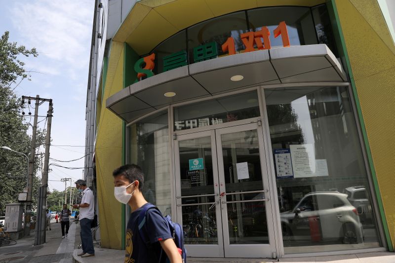 © Reuters. FILE PHOTO: A teenager walks past a closed outlet of Gaosi Education in Beijing, China August 23, 2021. REUTERS/Tingshu Wang/File Photo