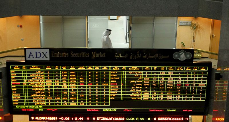 &copy; Reuters. متعامل خلف شاشة تعرض مؤشرات الأسهم في سوق أبوظبي للأوراق المالية بصورة من أرشيف رويترز.