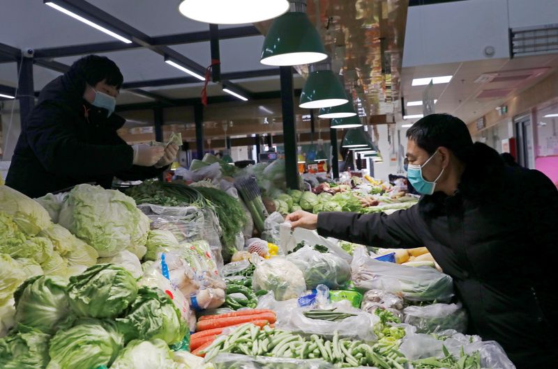 &copy; Reuters. FILE PHOTO: People wearing face masks shop at a market, following new cases of the coronavirus disease (COVID-19) in the country, in Beijing, China January 11, 2021. REUTERS/Tingshu Wang