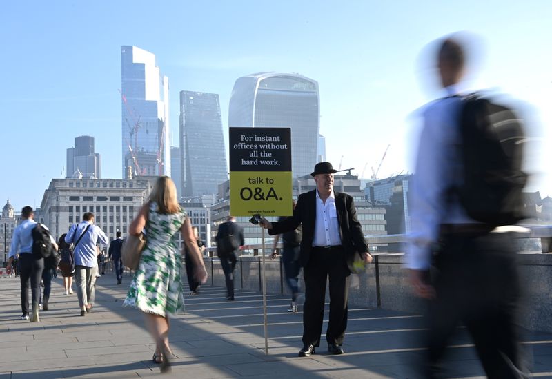 &copy; Reuters. FILE PHOTO: Workers pass by a sales person as they walk towards the City of London financial district as they cross London Bridge during the morning rush hour in London, Britain, September 8, 2021. REUTERS/Toby Melville