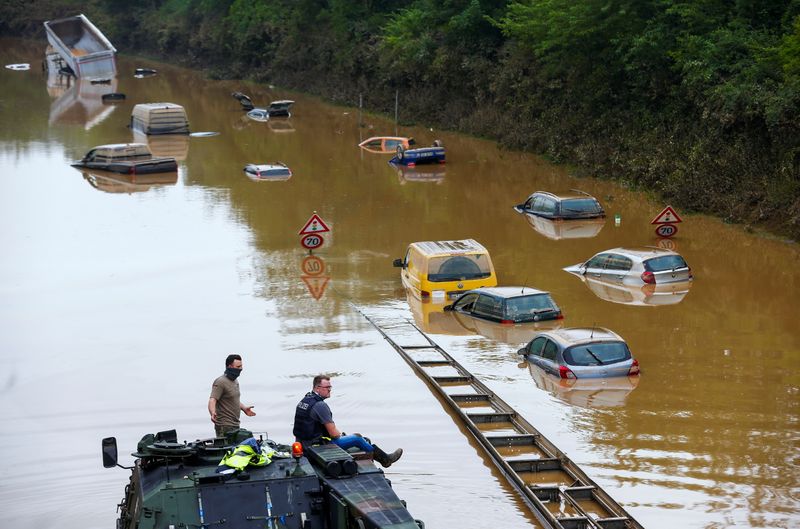 &copy; Reuters. FILE PHOTO: A police officer and a member of the Bundeswehr forces look at partially submerged cars on a flooded road following heavy rainfalls in Erftstadt-Blessem, Germany, July 17, 2021. REUTERS/Thilo Schmuelgen
