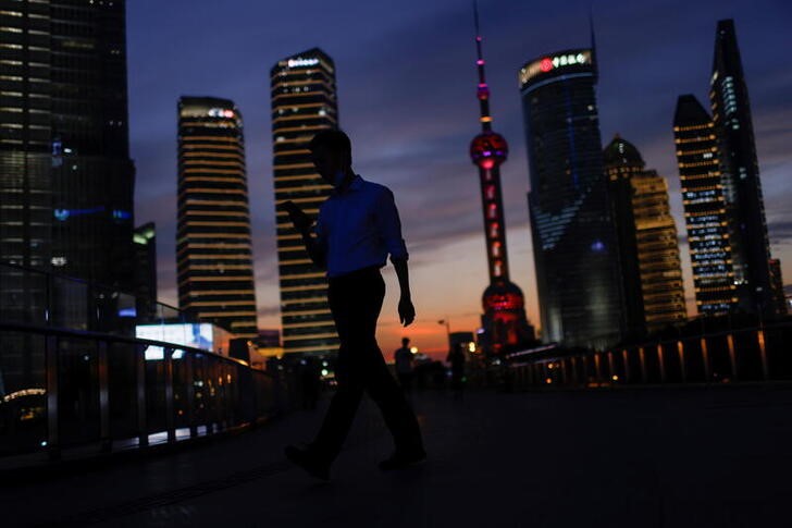 &copy; Reuters. A man checks his phone while walking in Lujiazui financial district during sunset in Pudong, Shanghai, China July 13, 2021. Picture taken July 13, 2021. REUTERS/Aly Song