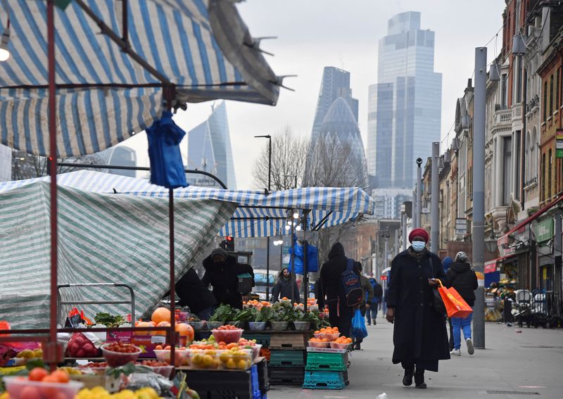 &copy; Reuters. FILE PHOTO: People shop at market stalls, with skyscrapers of the CIty of London financial district seen behind, amid the coronavirus disease (COVID-19) pandemic, in London, Britain, January 15, 2021. REUTERS/Toby Melville/File Photo