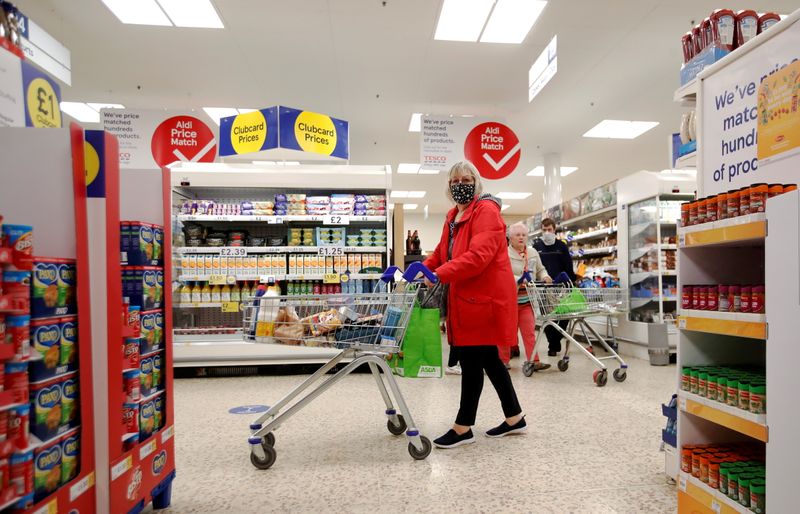 &copy; Reuters. FILE PHOTO: A woman wearing a face mask pushes a shopping cart at a Tesco supermarket in Hatfield, Britain October 6, 2020. REUTERS/Peter Cziborra
