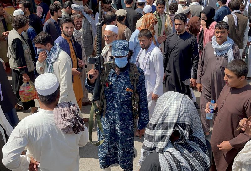 &copy; Reuters. FOTO DE ARCHIVO: Un miembro de las fuerzas de seguridad talibán monta guardia entre la multitud que pasa por una calle de Kabul, Afganistán, 4 de septiembre de 2021. REUTERS/Stringer