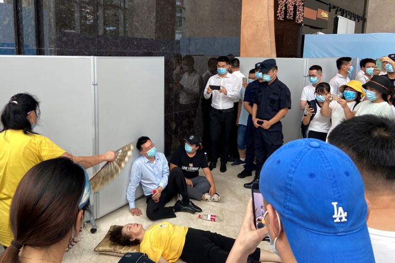 &copy; Reuters. A woman receives aid on the ground next to Du Jiang, the general manager and legal representative of Evergrande's wealth management division, while people gather to demand repayment of loans and financial products at the Evergrande's headquarters, in Shen