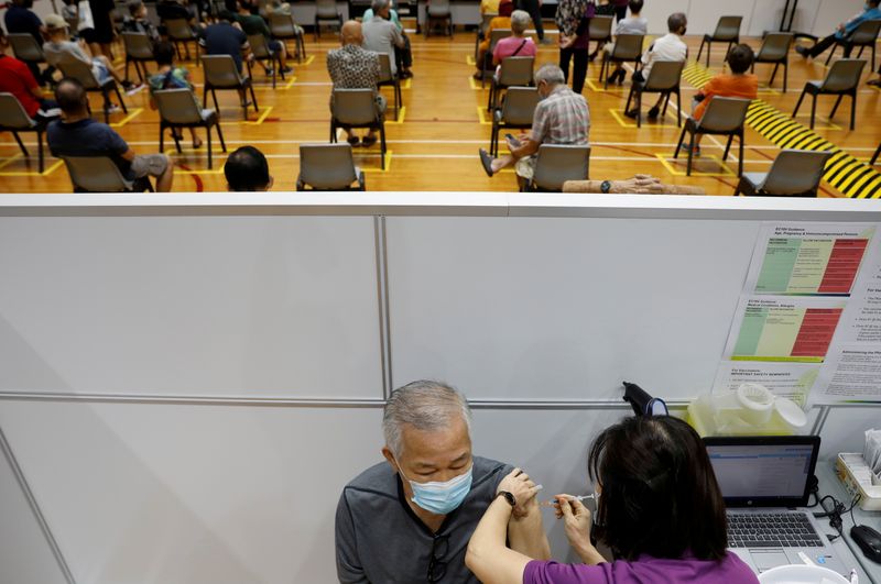 &copy; Reuters. 　９月１３日、シンガポールで先週末の新型コロナウイルスの新規感染が計１０００人を超え、１カ月前の１０倍に急増した。写真は３月８日、シンガポールでワクチン接種を受ける男性（