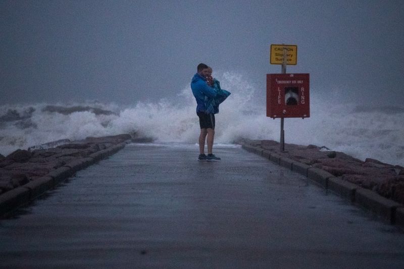 &copy; Reuters. Local resident John Smith holds his 18-month-old son Owen as he stands near breaking waves on a pier ahead of the arrival of Tropical Storm Nicholas in Galveston, Texas, U.S., September 13, 2021. REUTERS/Adrees Latif