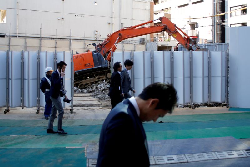 &copy; Reuters. FILE PHOTO: Businessmen walk past heavy machinery at a construction site in Tokyo's business district, Japan, January 16, 2017.    REUTERS/Toru Hanai/File Photo