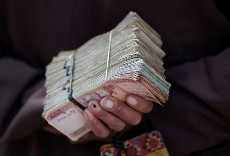 &copy; Reuters. FILE PHOTO: A money changer holds a stack of Afghan currency on a street in central Kabul April 2, 2014. REUTERS/Tim Wimborne/Files/File Photo