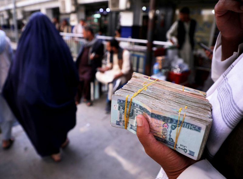 © Reuters. FILE PHOTO: A person holds a bundle of Afghan afghani banknotes at a money exchange market, following banks and markets reopening after the Taliban took over in Kabul, Afghanistan, September 4, 2021. REUTERS/Stringer/File Photo