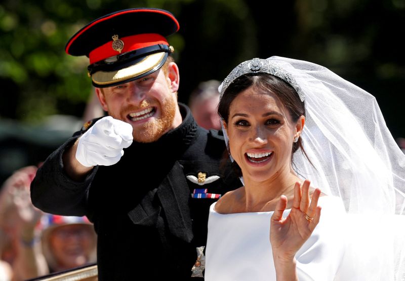 &copy; Reuters. FILE PHOTO: Britain’s Prince Harry gestures next to his wife Meghan as they ride a horse-drawn carriage after their wedding ceremony at St George’s Chapel in Windsor Castle in Windsor, Britain, May 19, 2018. REUTERS/Damir Sagolj