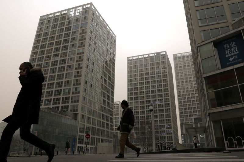 &copy; Reuters. FILE PHOTO: People walk past an office and commercial complex in Beijing's Central Business District (CBD), China March 15, 2021. REUTERS/Tingshu Wang/File Photo