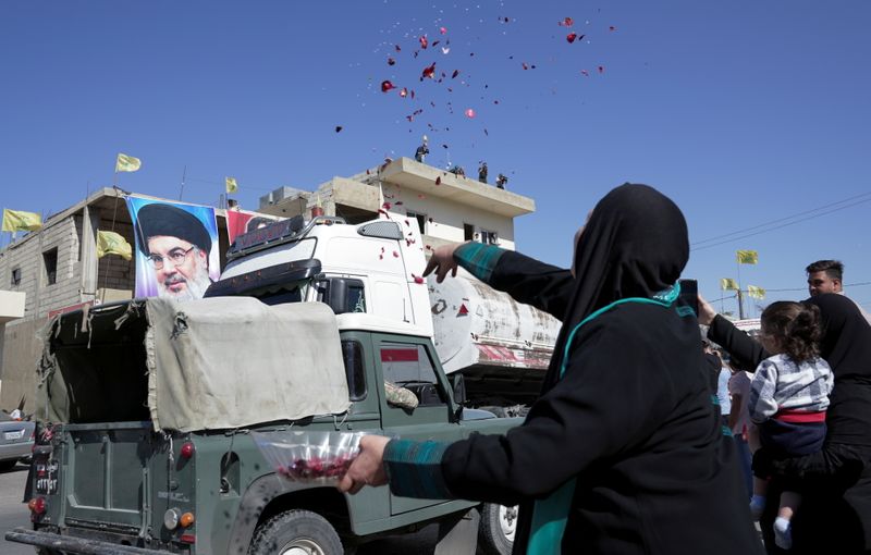 © Reuters. امرأة تلقي بالورود والأرز لدى مرور قافلة شاحنات تحمل زيت وقود إيراني في قرية العين بلبنان يوم الخميس. تصوير: عصام عبد الله - رويترز 