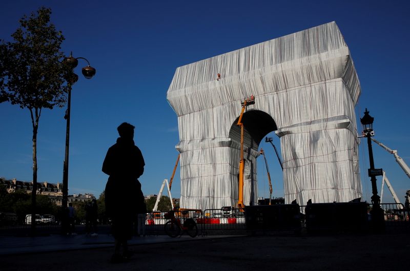 &copy; Reuters. 　フランス・パリの観光名所である凱旋門を銀色の再生利用可能な布で包み込むという芸術プロジェクトが完成し、マクロン大統領が１６日、式典に出席した（２０２１年　ロイター/GONZALO 