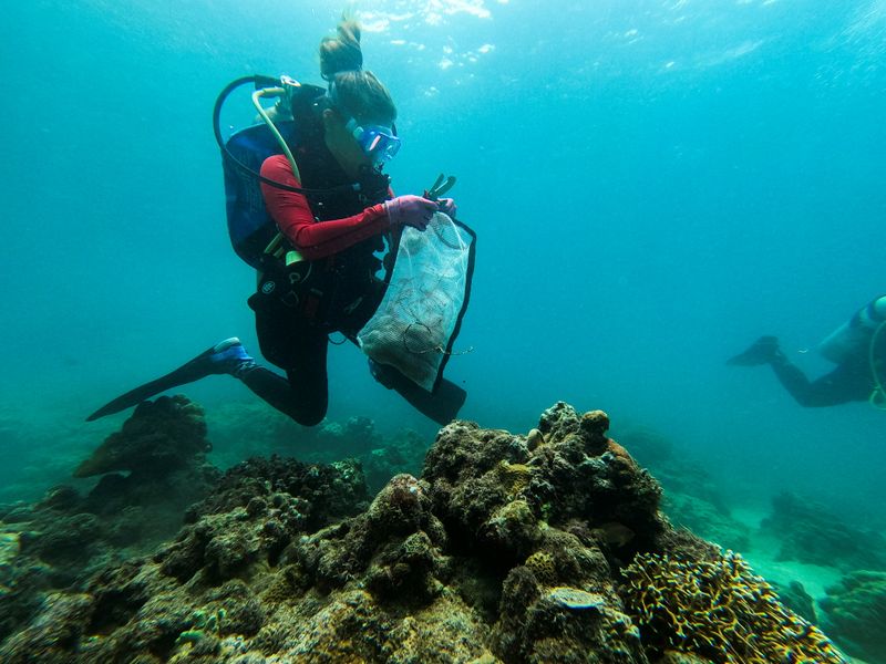 &copy; Reuters. Diving instructor Carmela Sevilla holds a mesh bag filled with trash during an underwater cleanup drive in Bauan, Batangas Province, Philippines, September 18, 2021. REUTERS/Peter Blaza
