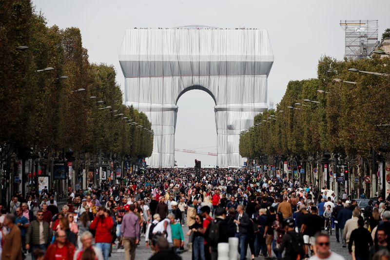 &copy; Reuters. أشخاص يسيرون بالقرب من نصب قوس النصر من تصميم الفنانين الراحلين كريستو وجين كلود في شارع الشانزليزيه خلال "يوم بلا سيارات" في باريس يوم الأح