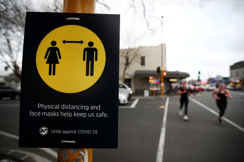 &copy; Reuters. FILE PHOTO: People jog past a social distancing sign on the first day of New Zealand's new coronavirus disease (COVID-19) safety measure that mandates wearing of a mask on public transport, in Auckland, New Zealand, August 31, 2020.  REUTERS/Fiona Goodall
