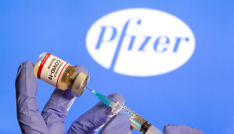 &copy; Reuters. FILE PHOTO: A woman holds a small bottle labeled with a "Coronavirus COVID-19 Vaccine" sticker and a medical syringe in front of displayed Pfizer logo in this illustration taken, October 30, 2020. REUTERS/Dado Ruvic